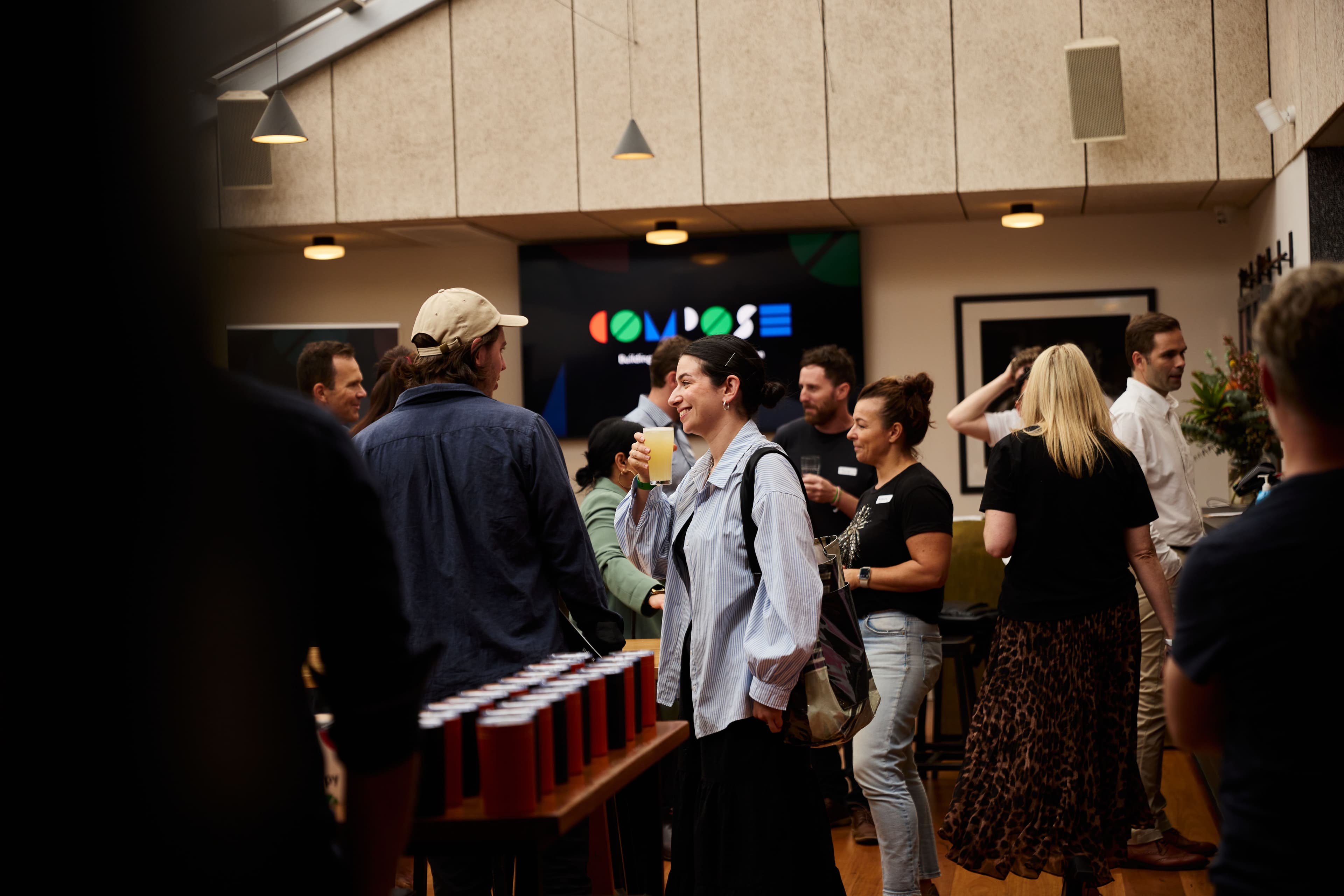 Group mingling at Compose event in a stylish room with a “COMPOSE” screen.